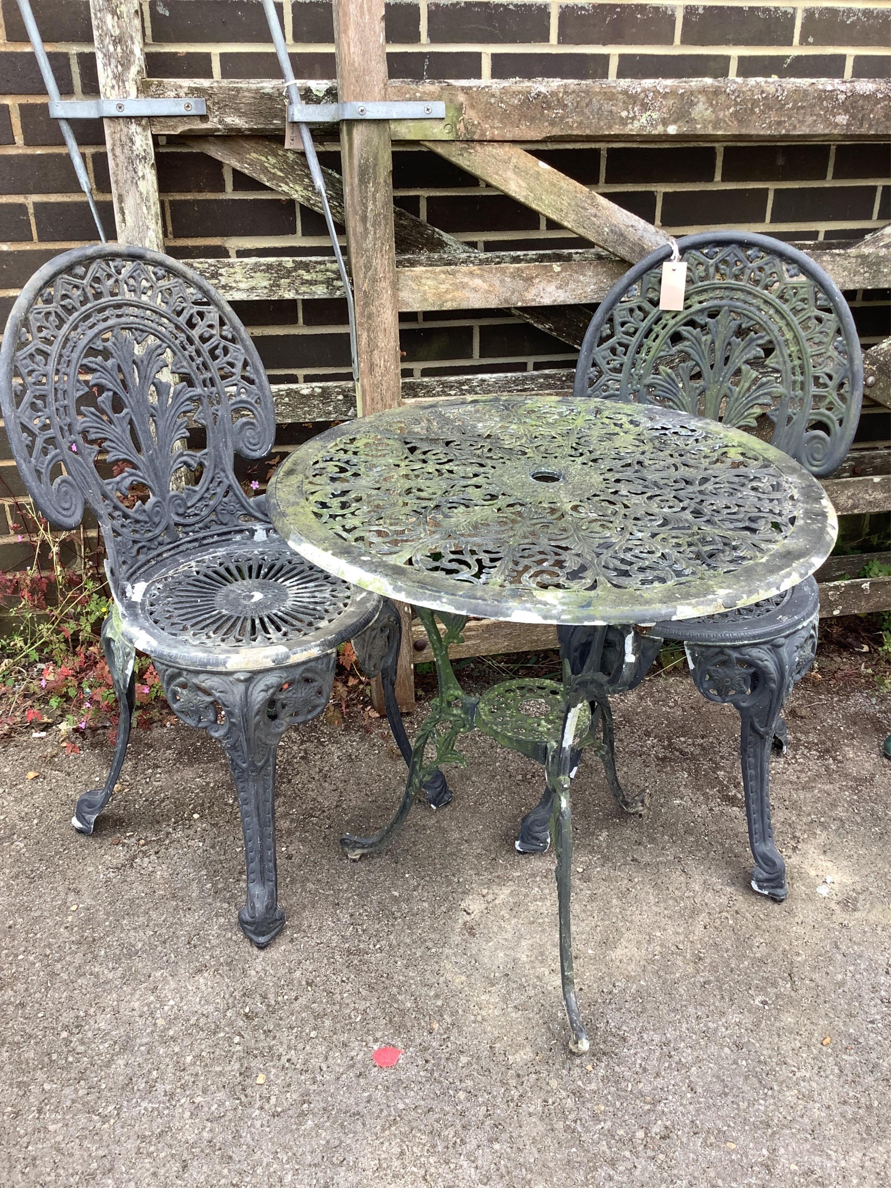 A Victorian style circular painted aluminium garden table, diameter 64cm, height 66cm, and two chairs. Condition - poor to fair